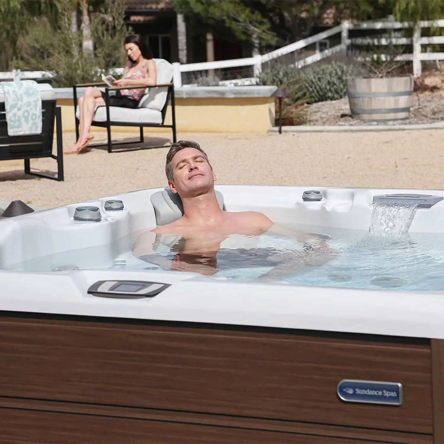 Husband Relaxing In A Sundance Hot Tub And Wife Reading A Book