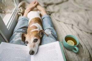 woman reading a book with a dog on her lap